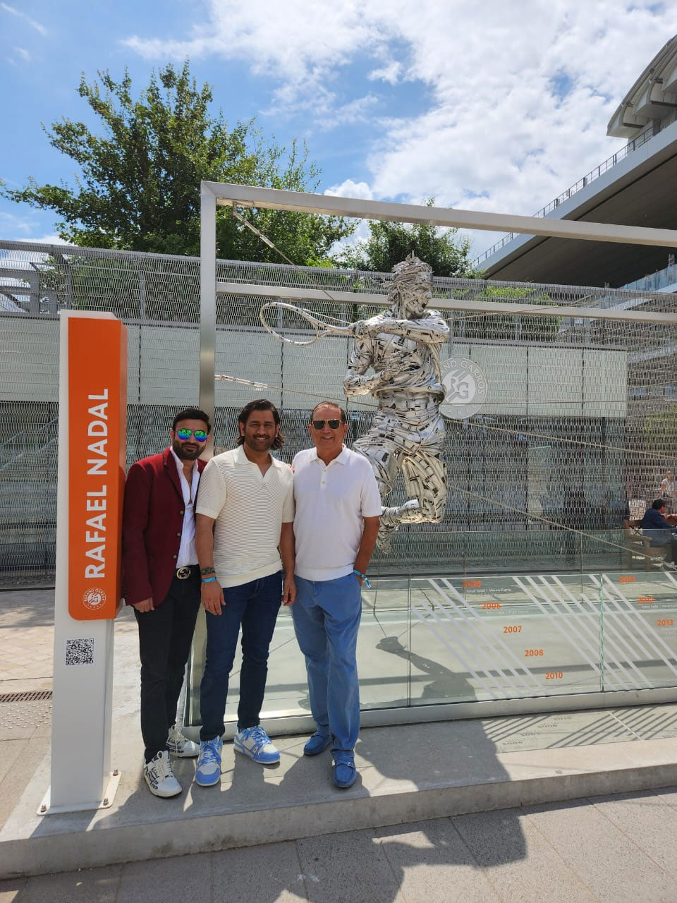 Three men standing in front of a tennis court