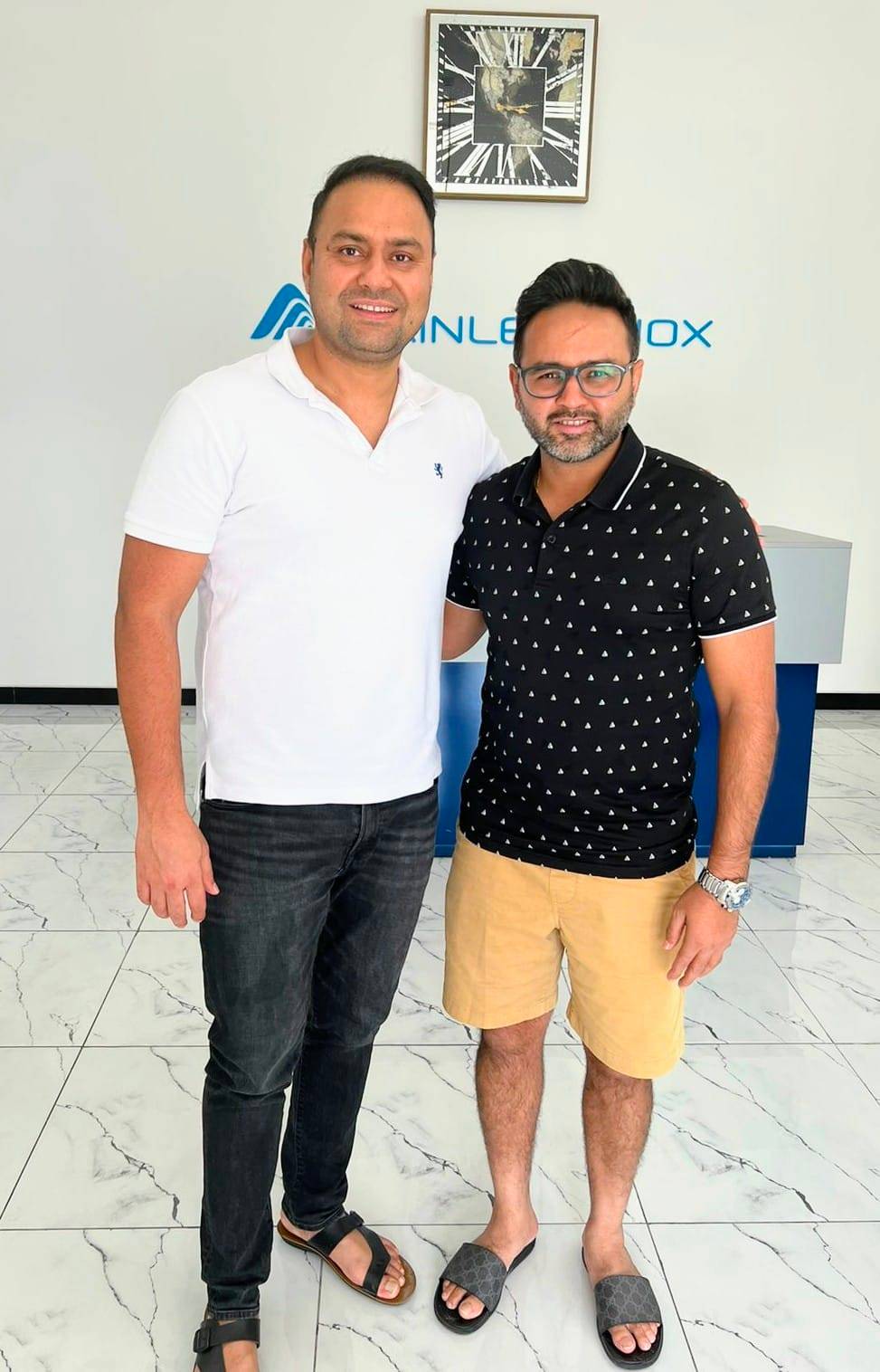 Two men standing in front of a white wall