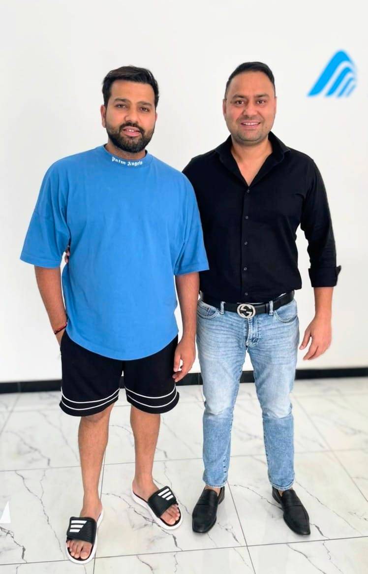 Two men standing together in front of a logo