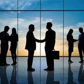 Silhouettes of business people shaking hands in front of large windows